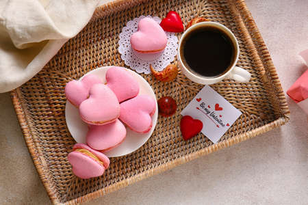 Tray with tasty heart-shaped macaroons and cup of coffee on light backgroundの写真素材