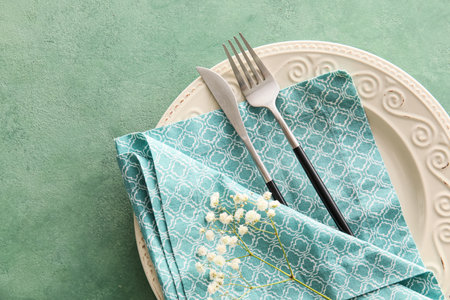 Beautiful table setting with flowers on green background