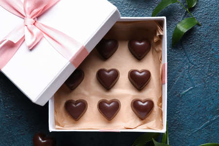 Box with tasty heart-shaped candies on dark color background, closeup