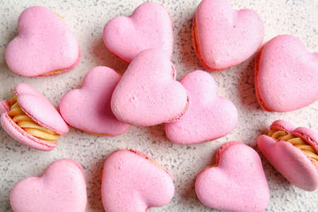 Tasty heart-shaped macaroons on light background