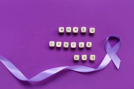 Awareness lavender ribbon and text WORLD CANCER DAY on color backgroundの写真素材