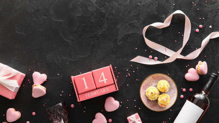 Calendar with date of Valentines Day and tasty cupcakes on dark background