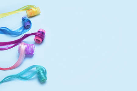 Different color hair strands with curlers on blue background