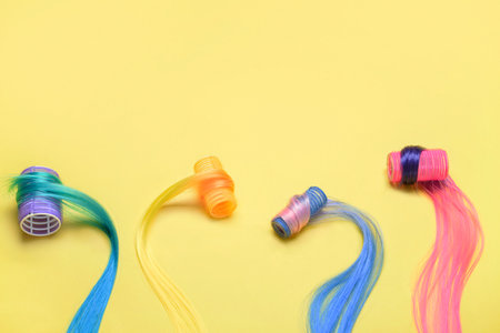 Different color hair strands with curlers on yellow backgroundの写真素材