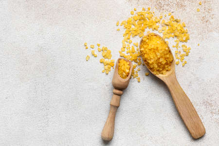 Wooden spoon and scoop with orange sea salt on light backgroundの写真素材