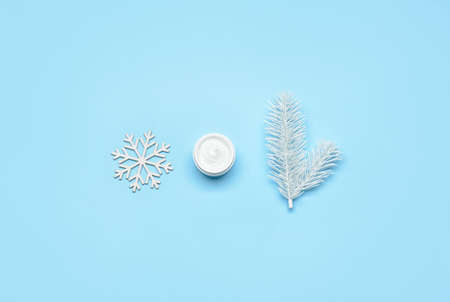 Snowflake, fir tree branch and jar with cream on color backgroundの写真素材
