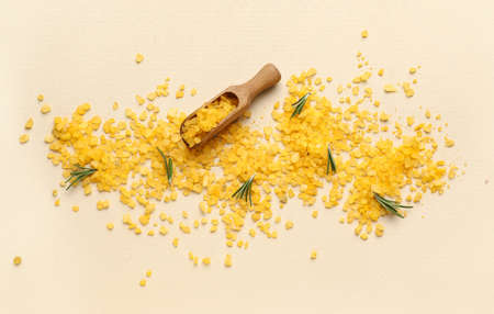 Wooden scoop of orange sea salt on color background