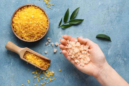 Female hand with sea salt on color background, closeupの写真素材