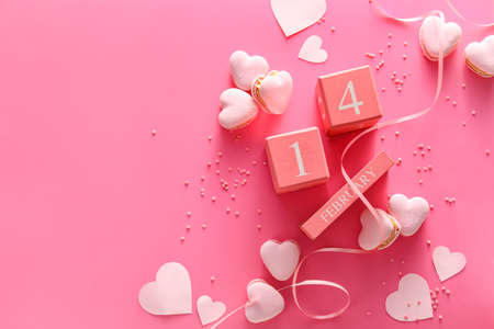 Calendar with date of Valentines Day and tasty macaroons in heart shape on pink backgroundの写真素材