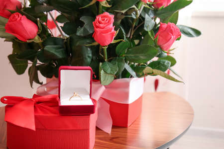 Boxes with beautiful roses and engagement ring on table in room, closeup. Valentine's Day...