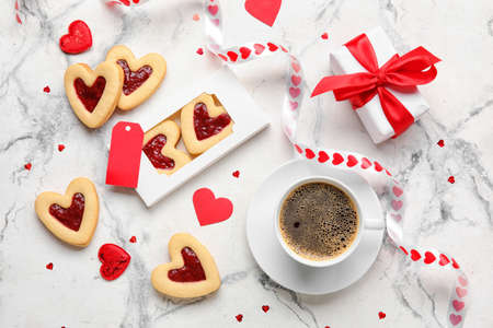 Tasty cookies in heart shape and cup of coffee on light backgroundの写真素材