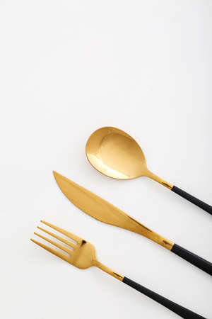 Set of stainless steel cutlery with black handle on white background, closeup