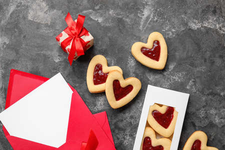 Tasty cookies in heart shape, gift box and blank envelope on dark backgroundの写真素材