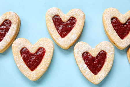 Tasty cookies in heart shape on blue background