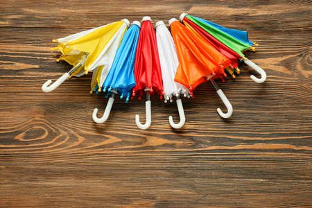 Different umbrellas on wooden background