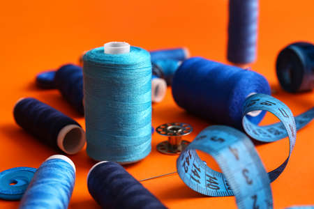 Thread spools and measuring tape on orange background, closeupの写真素材