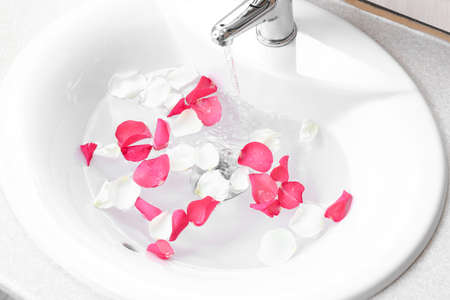 Sink with water and rose petals, closeup