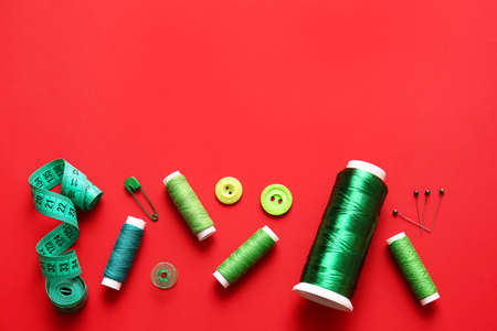 Thread spools with measuring tape and buttons on red backgroundの写真素材