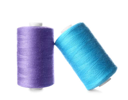 Blue and lilac sewing thread spools on white background