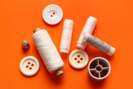 Thread spools and buttons on orange backgroundの写真素材