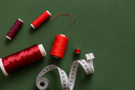 Thread spools and measuring tape on green background
