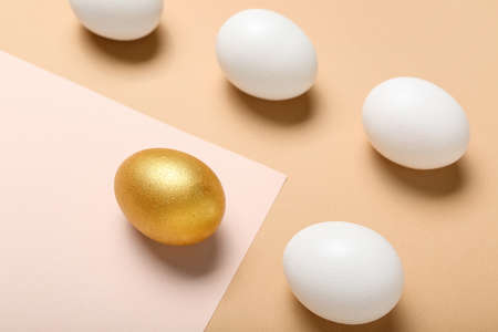 Golden Easter egg among white ones on color background, closeupの写真素材