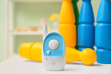 Modern baby monitor and bowling skittles on table in room