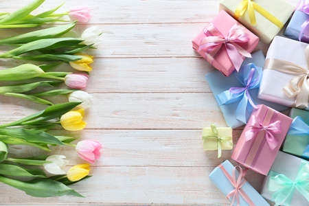 Composition with gift boxes and flowers for International Women's Day celebration on light wooden...
