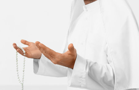 Praying young Muslim man on white background