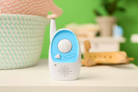 Modern baby monitor and baskets on table in room