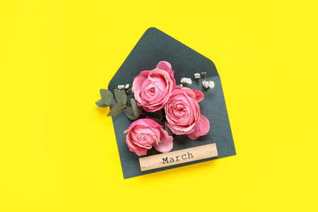Composition with envelope, beautiful flowers and word MARCH on yellow background