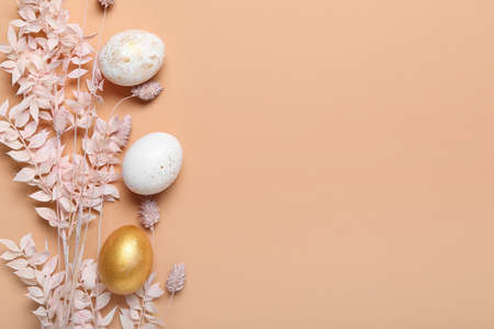 Beautiful Easter eggs and dried flowers on color backgroundの写真素材