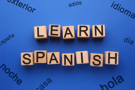 Text LEARN SPANISH made of wooden cubes on blue background, top viewの写真素材
