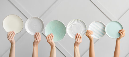 Hands with clean plates on light backgroundの写真素材