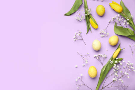 Composition with Easter eggs and beautiful flowers on lilac background