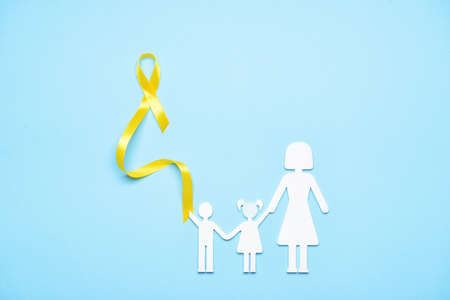 Golden awareness ribbon and silhouette of mother with children on blue background. International Childhood Cancer Dayの写真素材