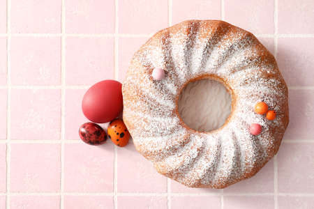 Plate with tasty Easter cake and eggs on tile background