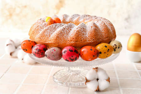 Dessert stand with tasty Easter cake and eggs on table