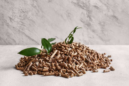 Pile of wood pellets and leaves on light background