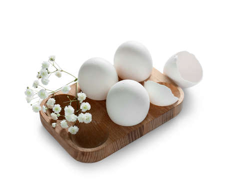 Wooden holder with Easter eggs and flowers on light background