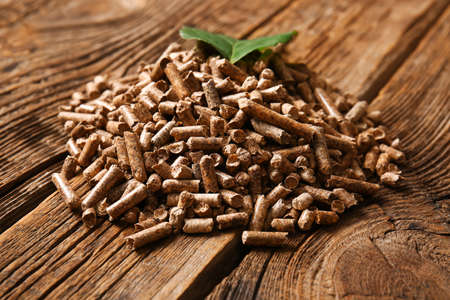 Pile of wood pellets on wooden background, closeup