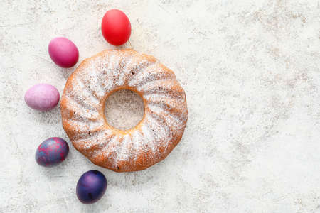 Tasty Easter cake and eggs on light background