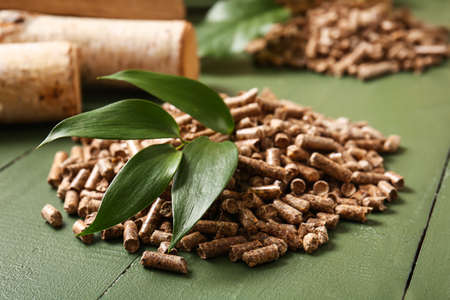 Pile of wood pellets on wooden background, closeup