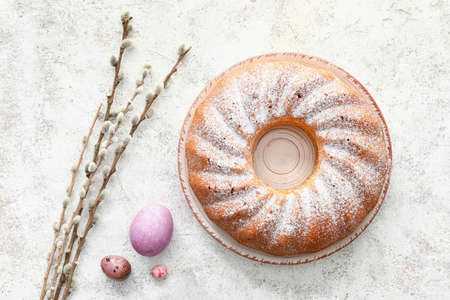 Plate with tasty Easter cake, willow branches and eggs on light backgroundの写真素材