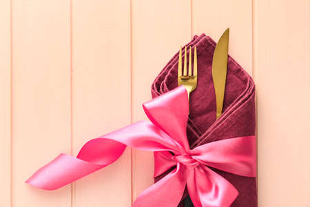 Elegant cutlery with ribbon on pink wooden backgroundの写真素材