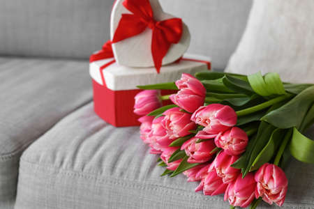 Bouquet of tulip flowers with gifts on sofaの写真素材