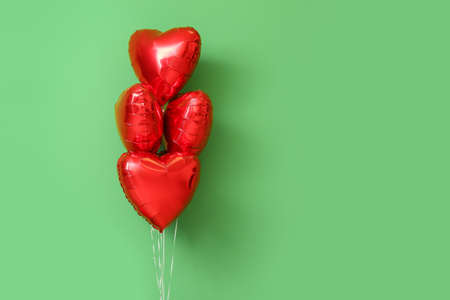 Beautiful heart-shaped balloons for Valentine's Day celebration on green background
