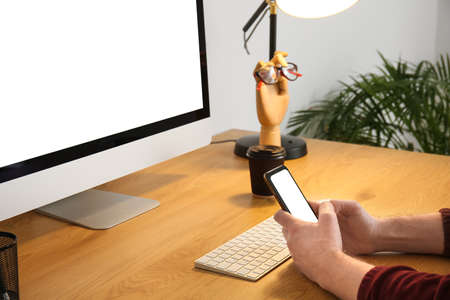 Man using modern mobile phone on wooden table