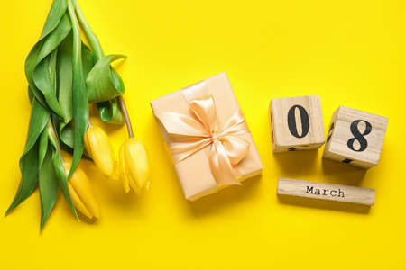 Wooden cube calendar with date MARCH 8, gift box and bouquet of tulips for International Women's Day...