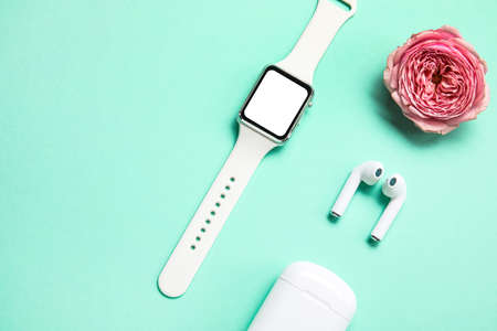 Smartwatch, earphones and peony flower on color background, closeup